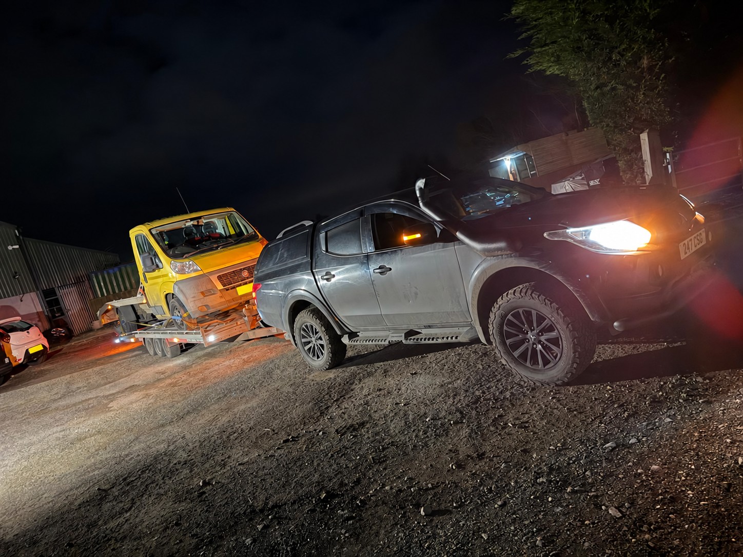 CSG pickup towing a yellow recovery truck after dark